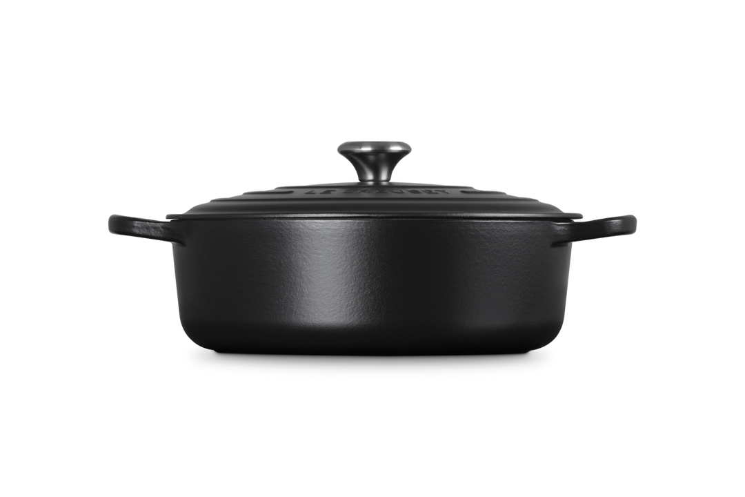 Black cast iron risotto pot with lid on a white background