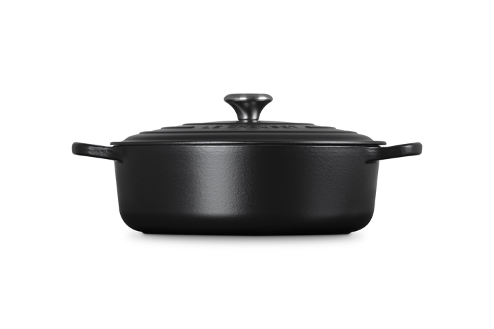 Black cast iron risotto pot with lid on a white background