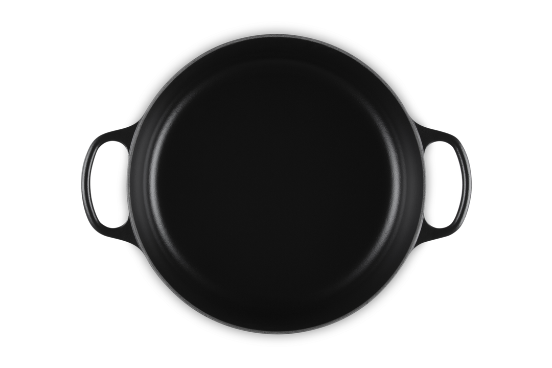 Black round risotto pot with handles on a white background