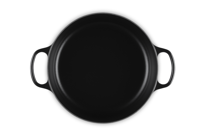 Black round risotto pot with handles on a white background