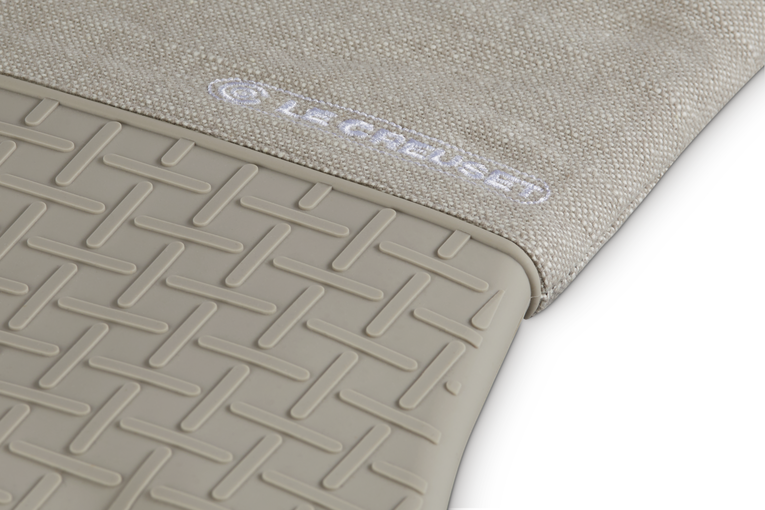 Close-up of a textured beige oven glove with a brand logo on a white background