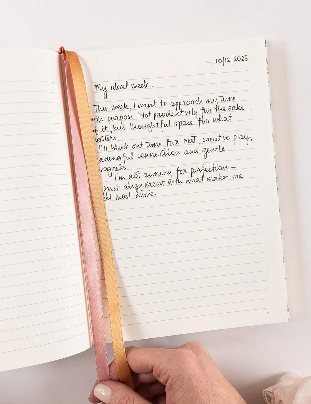 Handwritten notes in a notebook with a pen held open