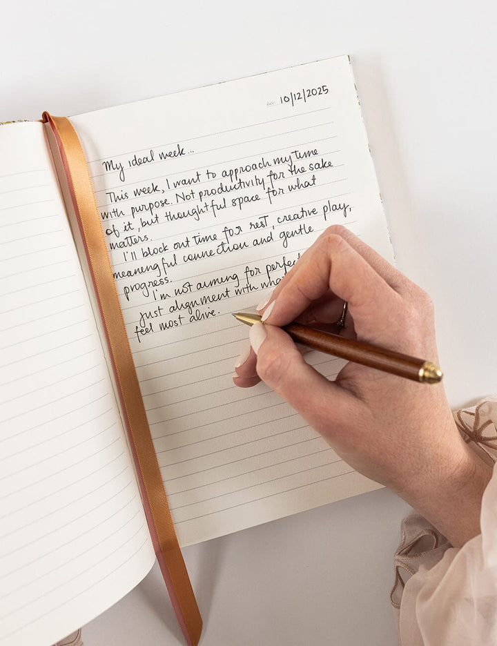 Hand writing in a journal with a pen on a white background