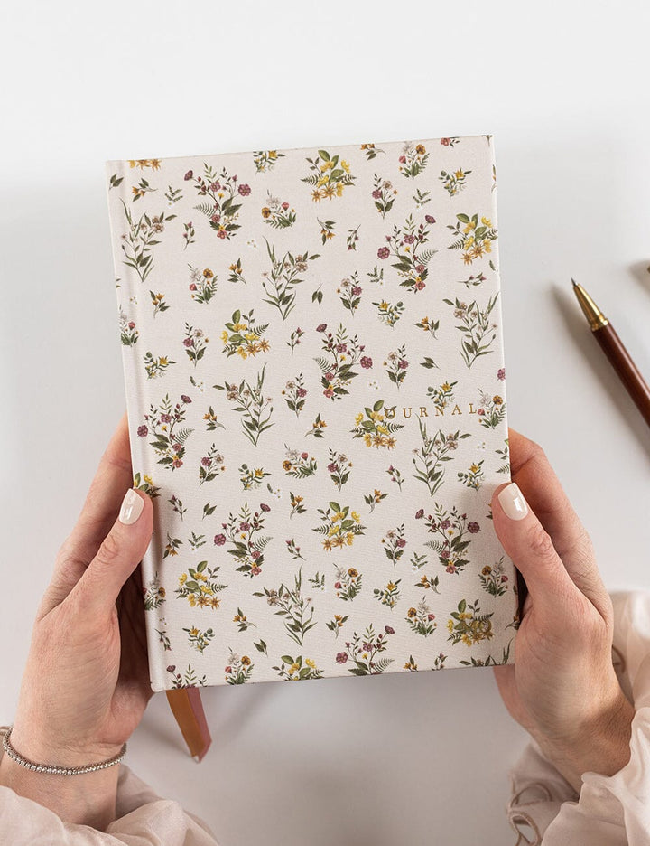 Floral-patterned notebook held by hands on a light background