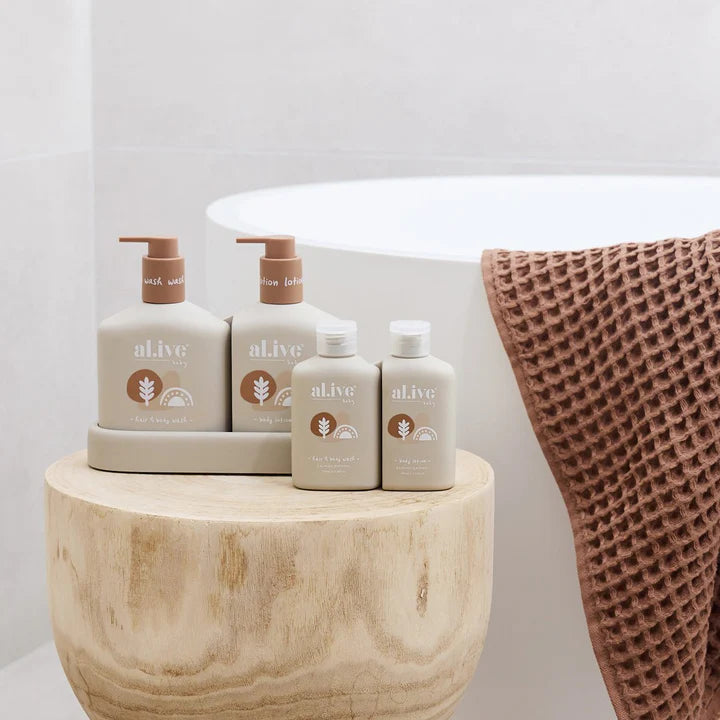 Set of 'alive' skincare products on a wooden table with a soft blanket in the background.