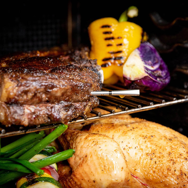 Grilled steak, corn on the cob, and potato on a grill