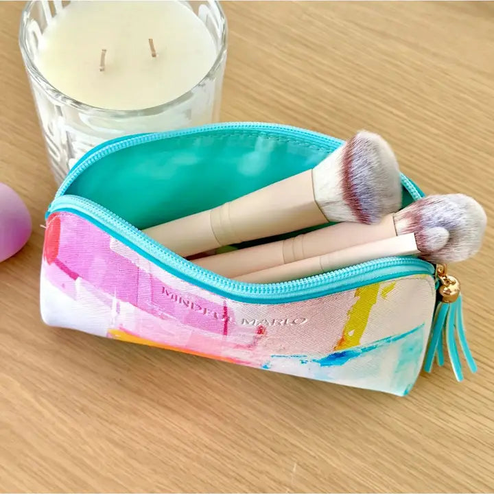 Colorful makeup pouch with brushes and a candle on a wooden surface