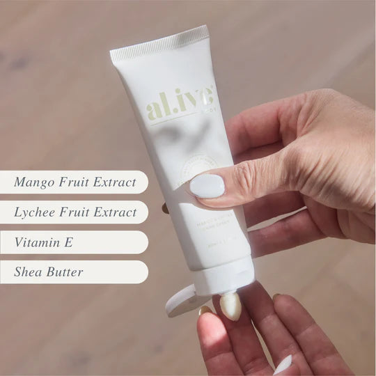 Hand holding a tube of 'alive' cream with ingredients listed on a wooden surface