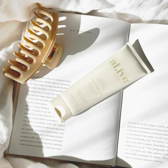 Wooden hair comb and white tube of cream on an open book