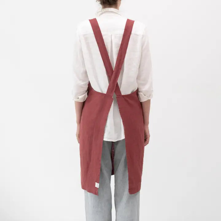 Person wearing a red apron over a white shirt on a white background