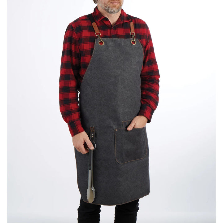 Person wearing a gray apron over a red and black plaid shirt on a white background