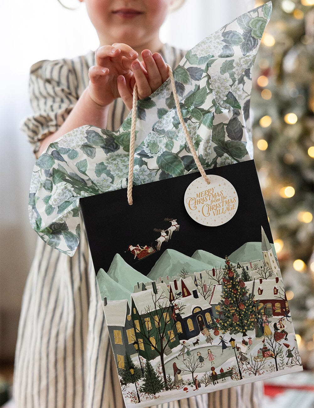 Person holding a Christmas-themed gift bag with festive design