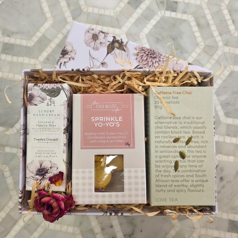 Gift set with hand cream, tea, and other items on a decorative surface