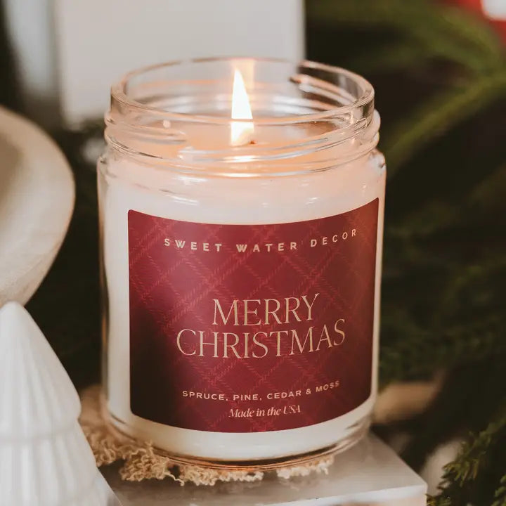 Candle in a jar with a 'Merry Christmas' label on a decorative stand.