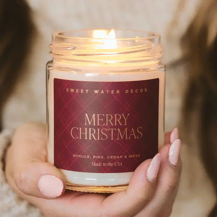 Candle with a 'Merry Christmas' label held by a person