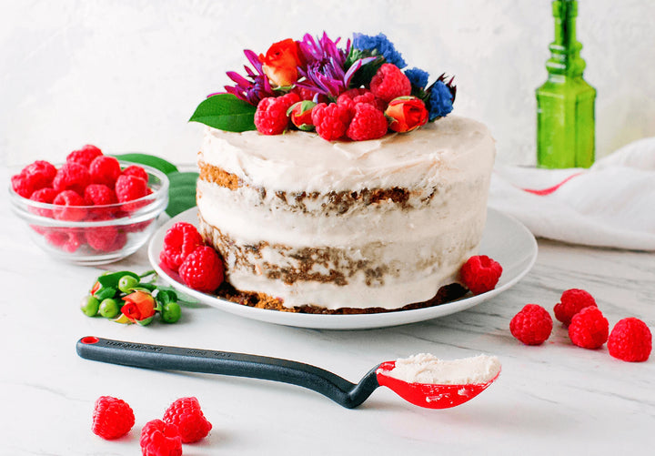 Naked cake with white frosting and fresh berries on a white surface