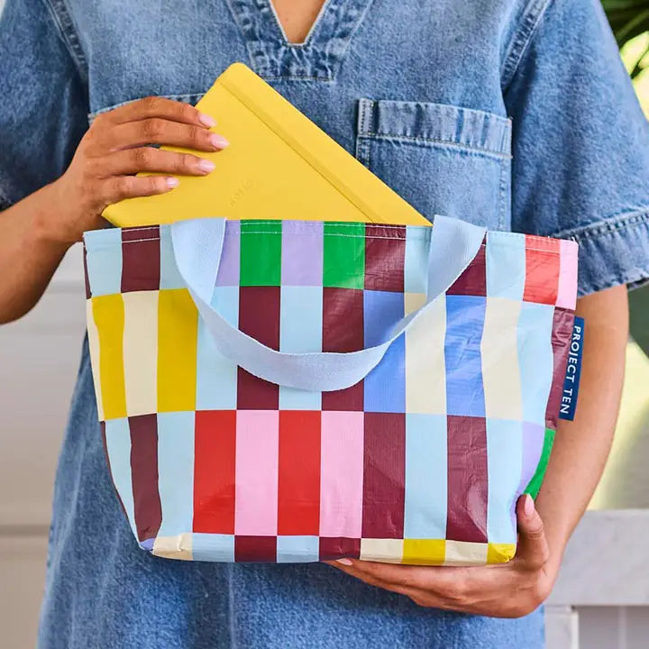 Person holding a colorful checkered bag with a yellow top