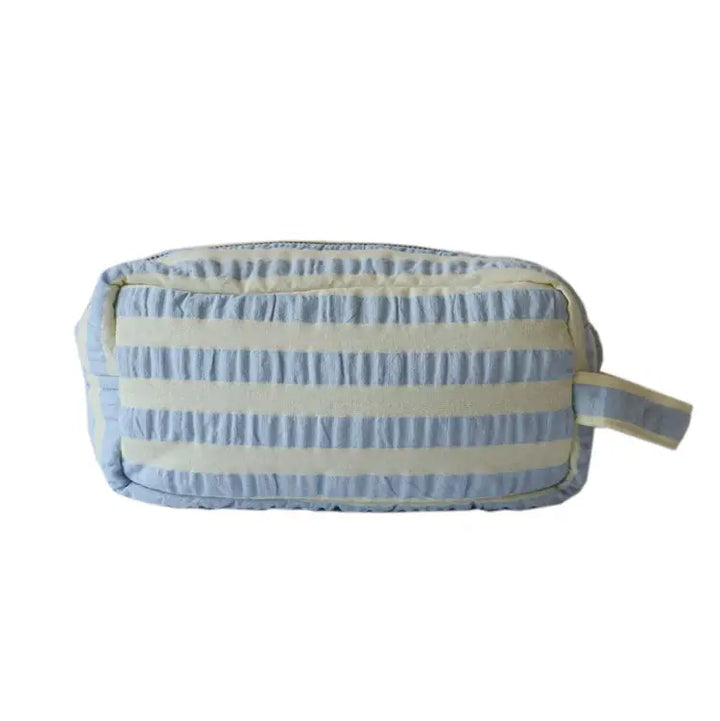 Striped toiletry bag with blue and beige pattern on a white background