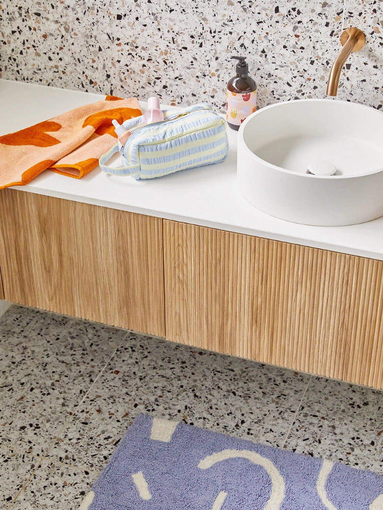 Bathroom setting with a sink, towel, and toiletries on a countertop.