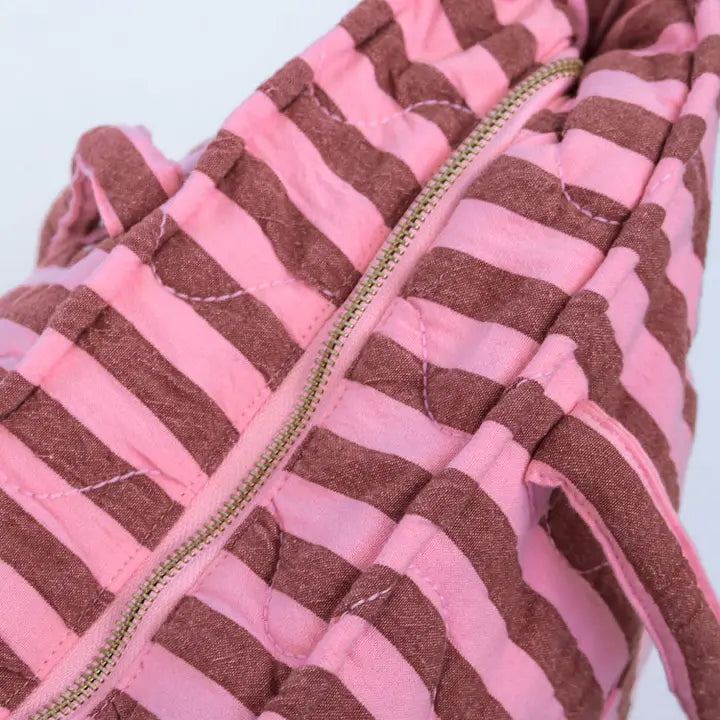 Close-up of a pink and brown striped fabric with a zipper.