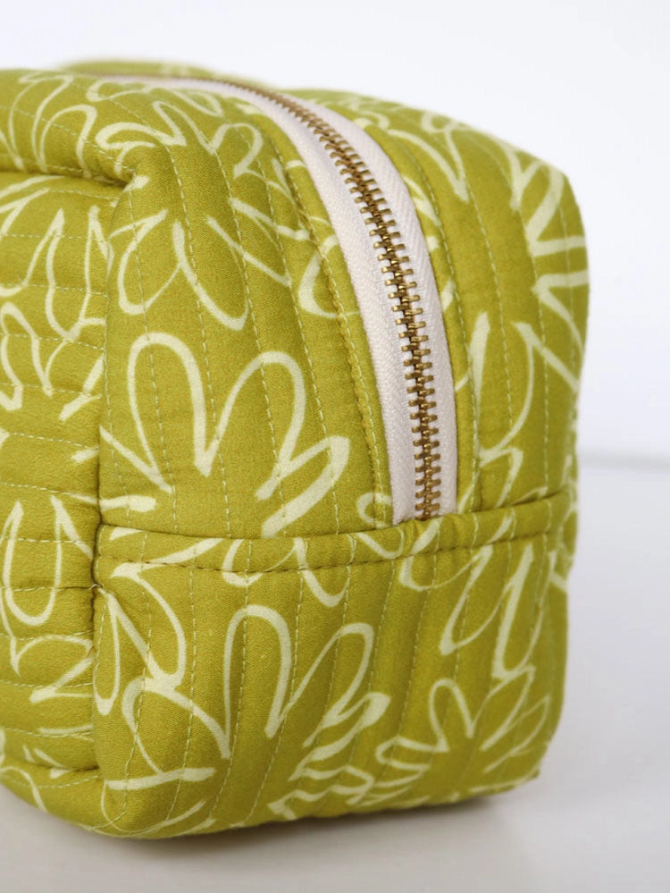 Green and white patterned toiletry bag with a zipper on a light gray background