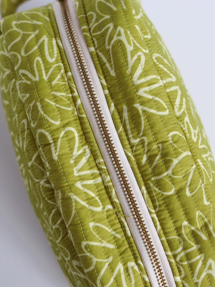 Green fabric pouch with white floral pattern and gold zipper on a white background