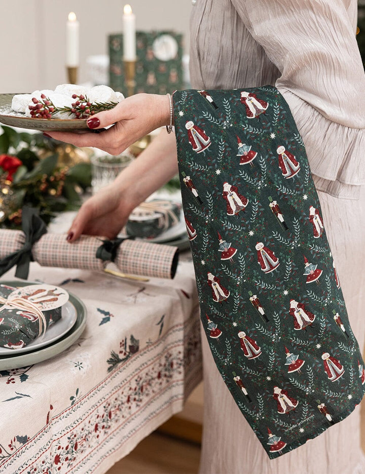 Christmas linen tea towel with santa claus over someones arm at festive set christmas table