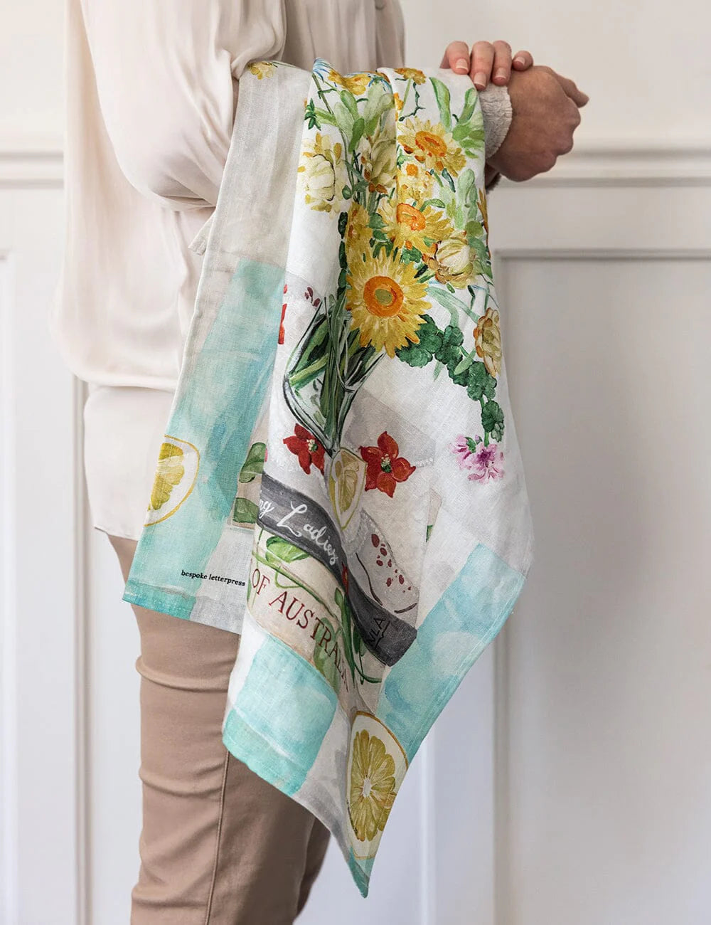 Person holding a floral-patterned towel with text and graphics.