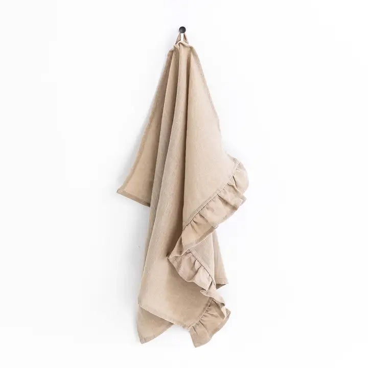 Beige towel with ruffled edges hanging on a white background