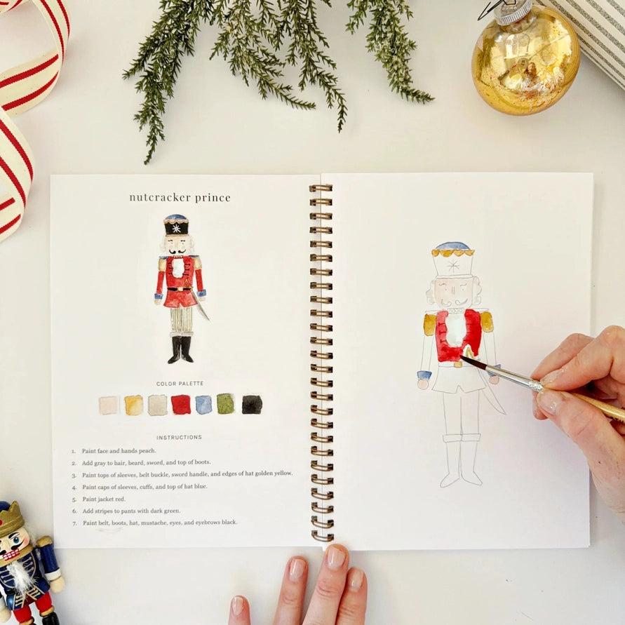 Open watercolour workbook, with a hand panting a Nutcracker