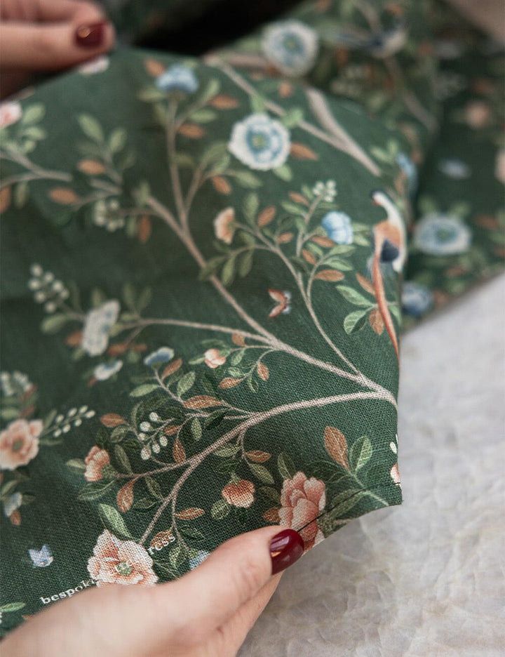 Close-up of green floral linen tea towel held by a hand with red nail polish.