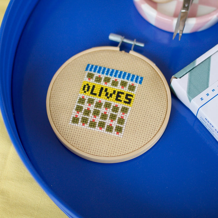 Cross stitch of an olive jar on a blue tray 