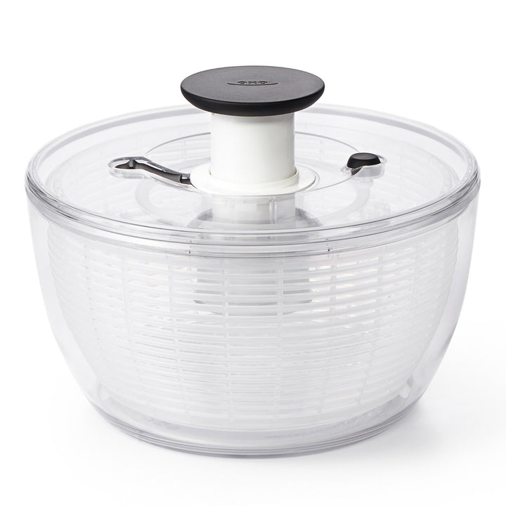 Clear salad spinner with black lid on a white background