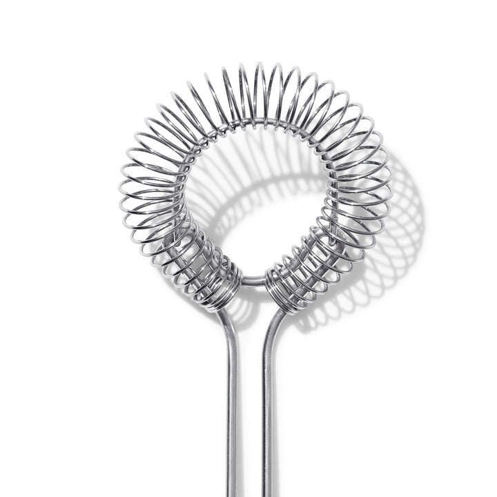 Metallic sauce and gravy whisk on a white background