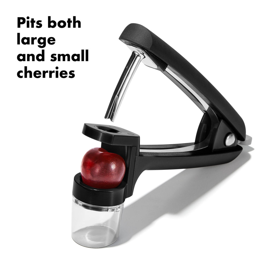 Black cherry pitter with a cherry in it on a white background