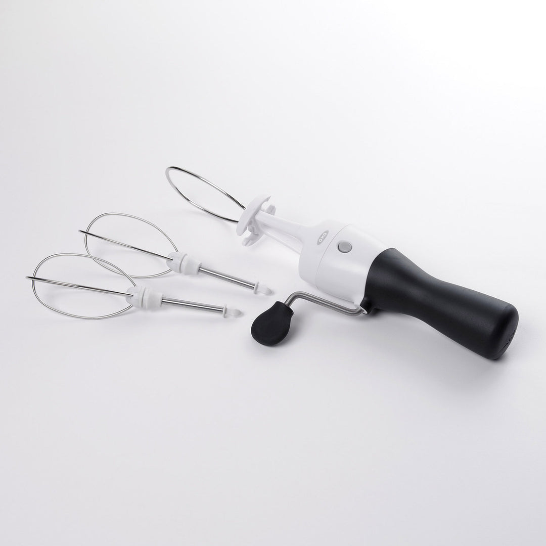 Handheld egg beater with attachments on a white background