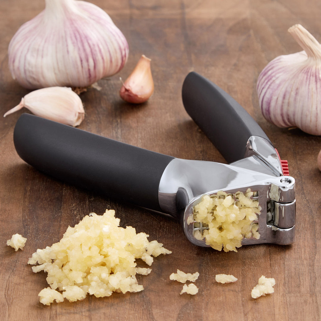 Garlic press with minced garlic on a wooden surface