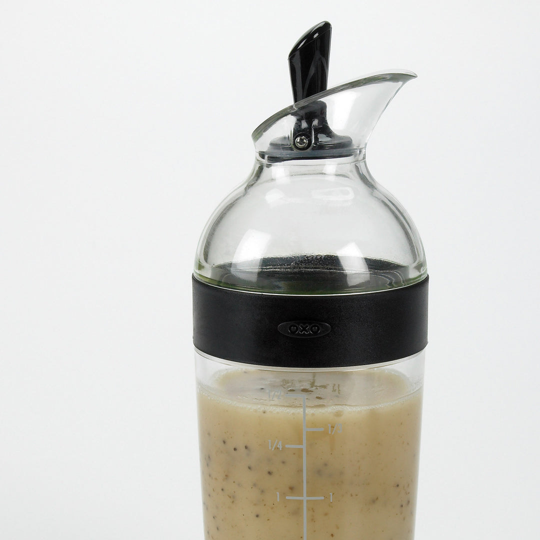 Glass bottle with black lid containing a liquid on a white background
