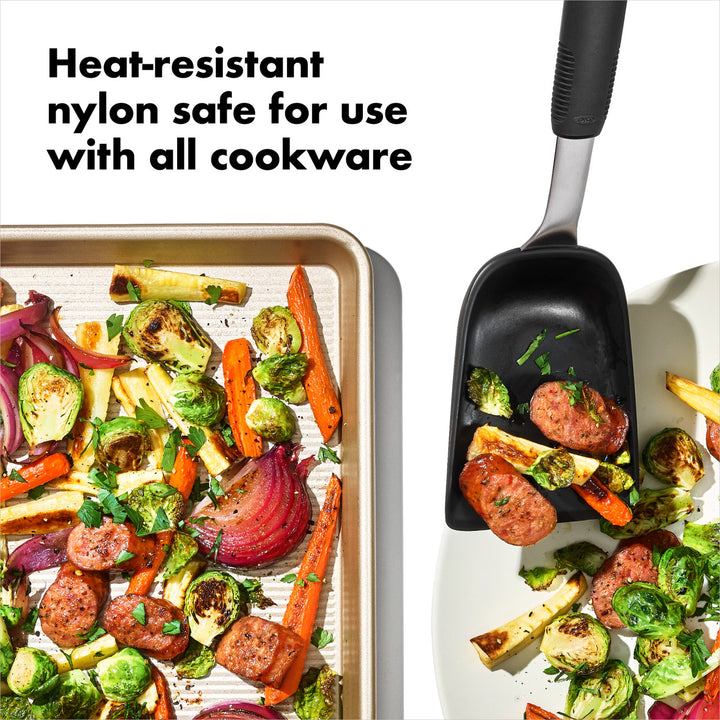 Black heat-resistant spatula with roasted vegetables on a white background