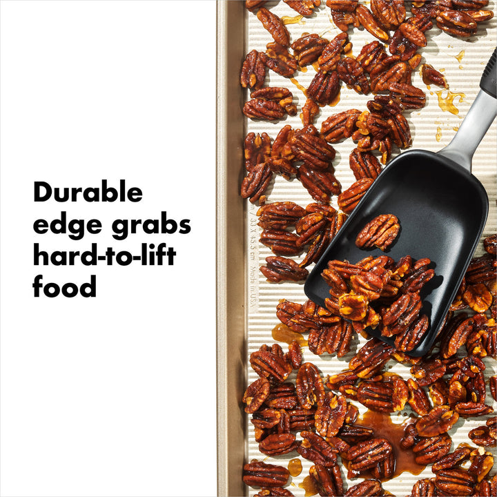 Black scoop lifting roasted pecans from a baking sheet with text &