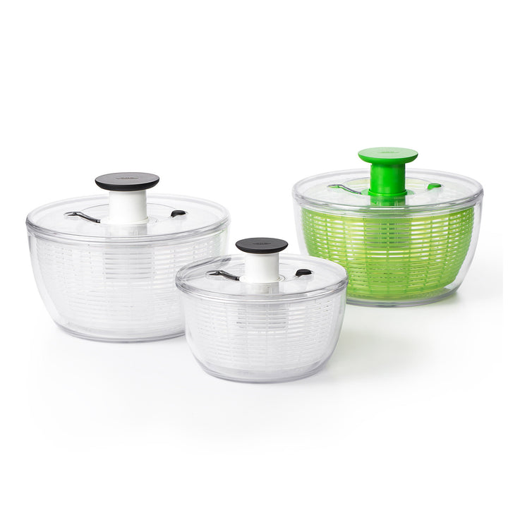 Set of three salad spinners with clear and green containers on a white background