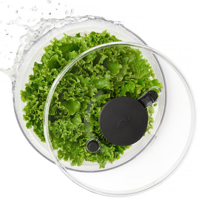 Clear salad spinner with fresh green lettuce on a white background