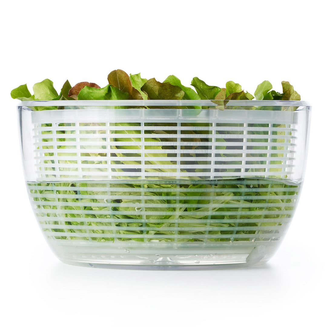 Clear salad spinner with green lettuce on a white background