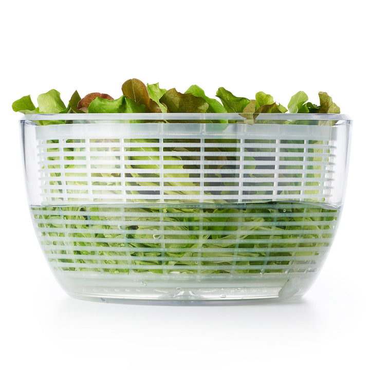 Clear salad spinner with green lettuce on a white background