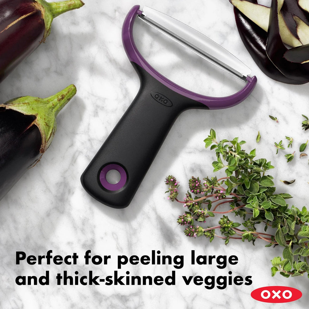 Oxo vegetable peeler with eggplants and herbs on a marble surface