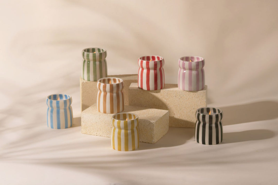 Set of colorful striped ceramic candles on a neutral background