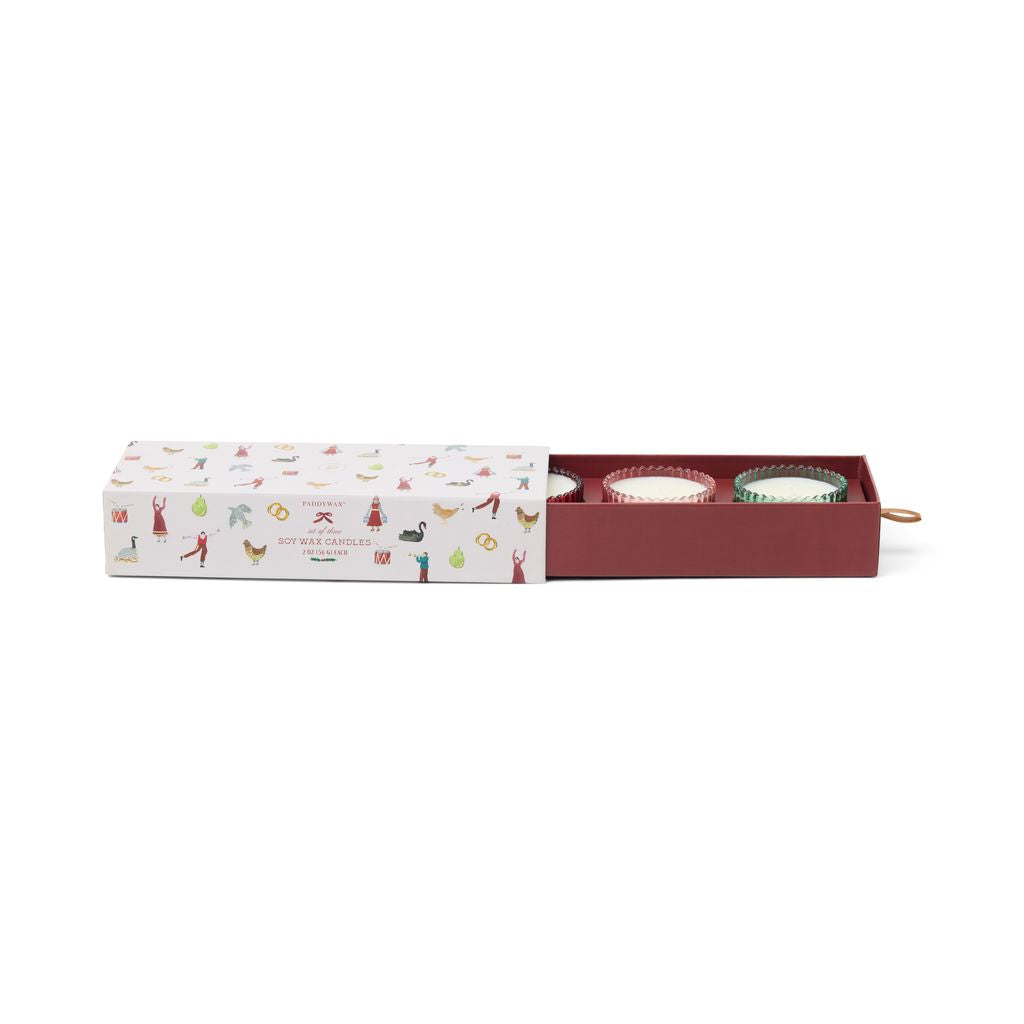 Three small candles in a decorative box with illustrations on a white background