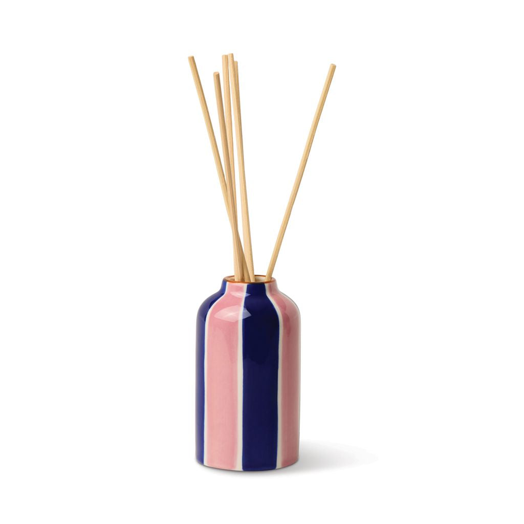 Pink and blue striped diffuser bottle with wooden sticks on a white background