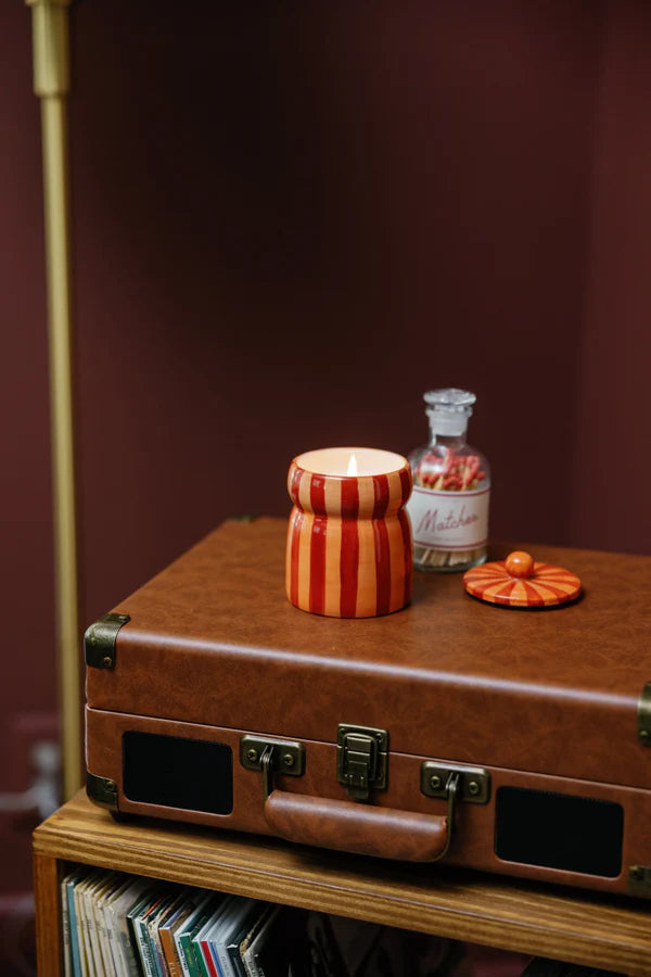 Brown suitcase with candle and decorative item on a wooden surface against a dark background