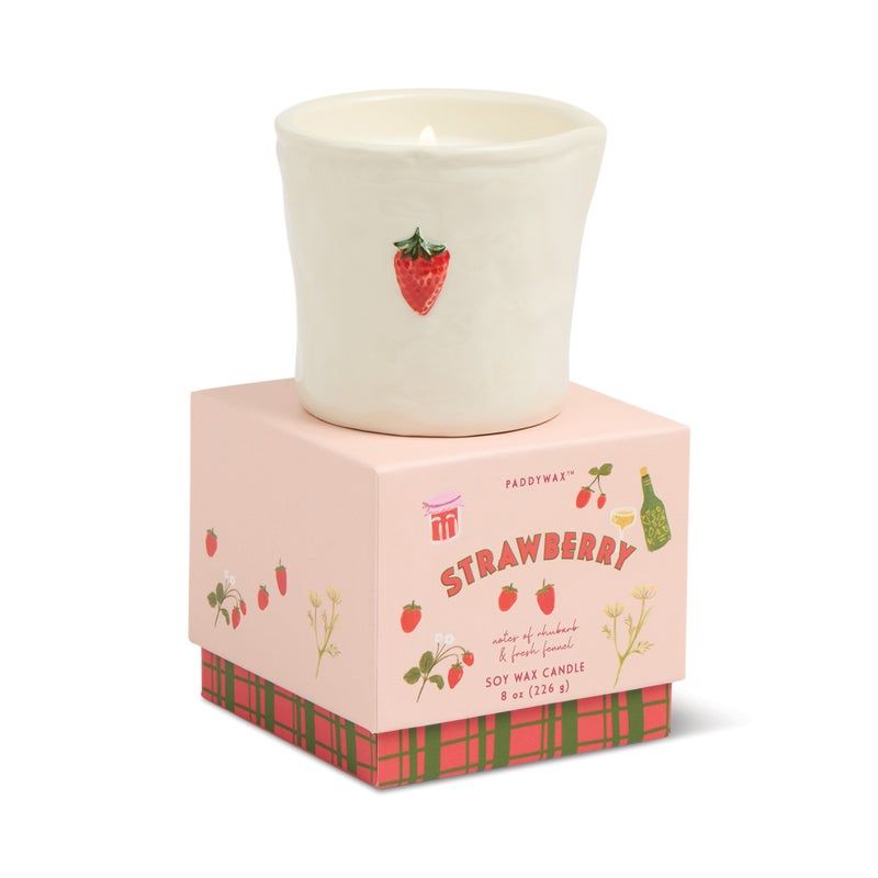 Candle in a decorative vessel with strawberry design on a white background